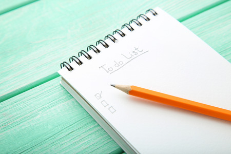 To do list in notepad with pencil on wooden table