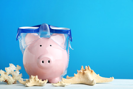 Pink piggy bank with diving mask and snorkel on wooden tableの写真素材