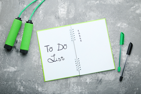 To do list in notepad with pens and skipping rope on grey wooden tableの写真素材