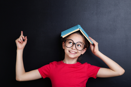 Young girl with book and glasses on blackboard backgroundの写真素材