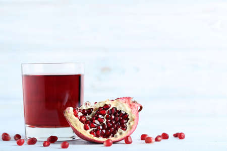 Pomegranate fruit and juice in glass on wooden tableの写真素材