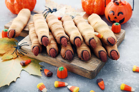 Halloween finger cookies on cutting board with candiesの写真素材