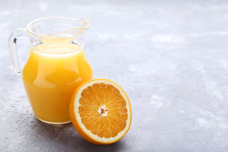 Orange fruit with jug of juice on grey wooden tableの写真素材