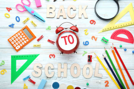 Inscription Back To School with school supplies on wooden table