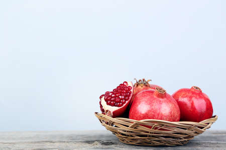 Ripe and juicy pomegranate in basket on grey wooden tableの写真素材
