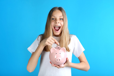 Young girl with piggy bank on blue backgroundの写真素材