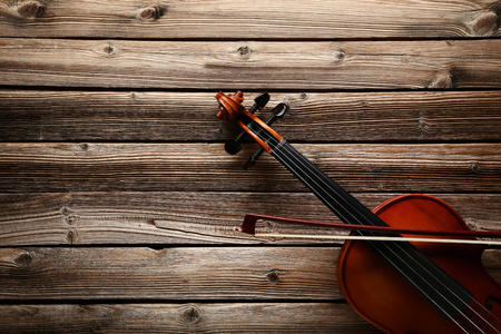 Violin with bow on brown wooden tableの写真素材