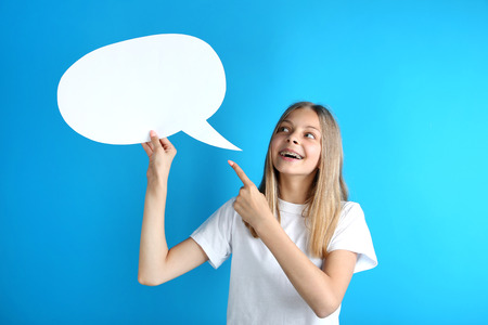 Young girl holding speech bubble on blue backgroundの写真素材