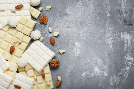 Chocolate pieces with coconut candies and nuts on wooden tableの写真素材