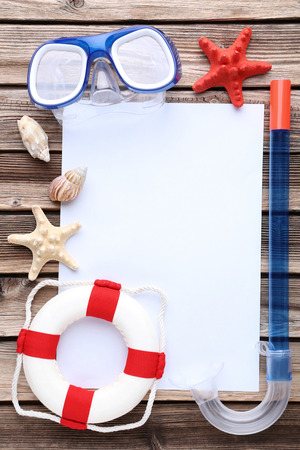 Blank sheet of paper with seashells and dive mask on wooden tableの写真素材