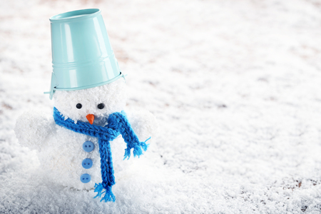 Small snowman toy with bucket on white snowの写真素材