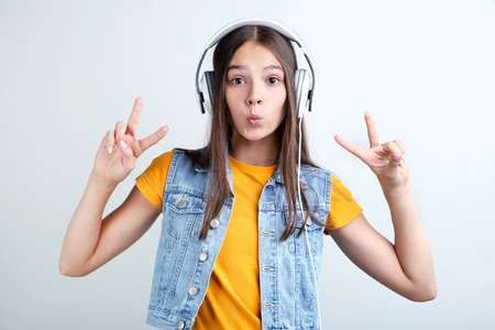 Young girl with headphones on grey background