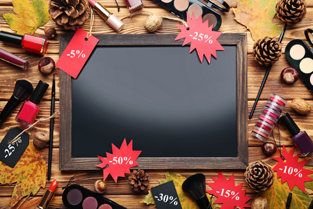 Makeup cosmetics with sale tags, dry leafs and wooden frameの写真素材