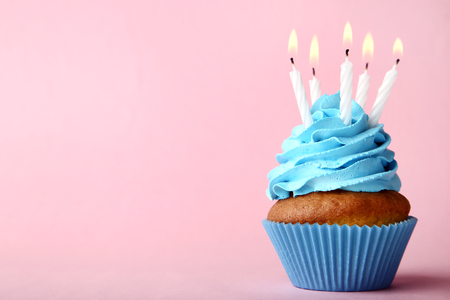 Tasty cupcake with candles on pink backgroundの写真素材