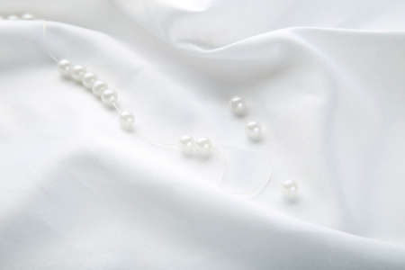 Pearl necklace on white satin fabricの写真素材