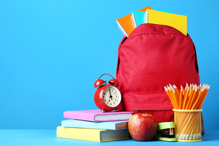 Red backpack with school supplies on blue backgroundの写真素材