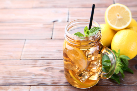 Ice tea in glass jar with lemon and mint leafs on wooden tableの写真素材