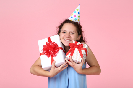 Beautiful young girl with gift boxes on pink backgroundの写真素材