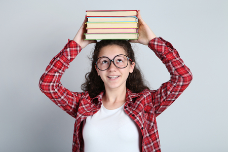 Beautiful young girl with books on grey backgroundの写真素材