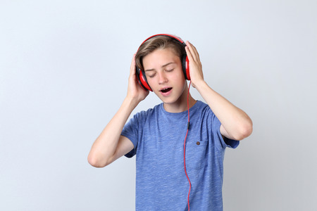 Cute teenager with headphones on grey backgroundの写真素材