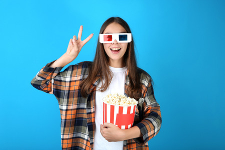 Young girl holding bucket with popcorn on blue background
