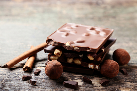 Chocolate pieces with nuts and candy balls on wooden tableの写真素材
