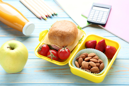 School lunch box with sandwich and bottle of juice on wooden tableの写真素材