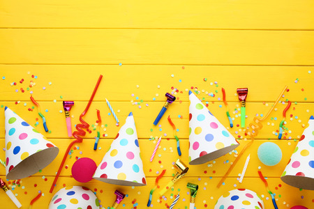 Birthday paper caps with candles and blowers on yellow wooden tableの写真素材