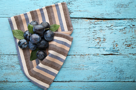 Ripe and sweet plums with napkin on blue wooden tableの写真素材