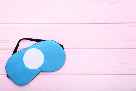 Sleeping mask on pink wooden tableの写真素材