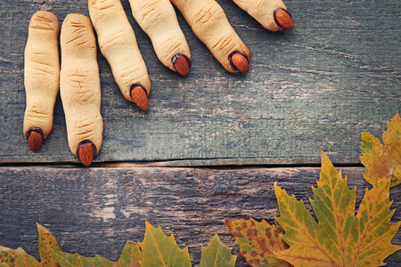 Halloween finger cookies with dry leafs on wooden tableの写真素材