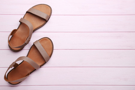 Female beige sandals on pink wooden tableの写真素材