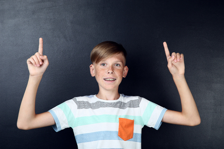Beautiful young boy with dental braces on blackboard backgroundの写真素材