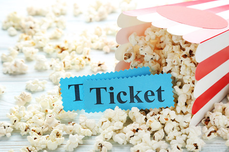 Popcorn in striped bucket and paper with inscription Ticket on wooden tableの写真素材
