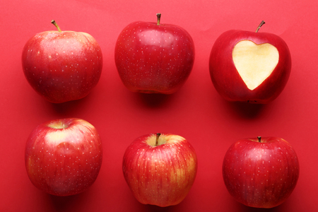 Fresh and ripe apples on red backgroundの写真素材