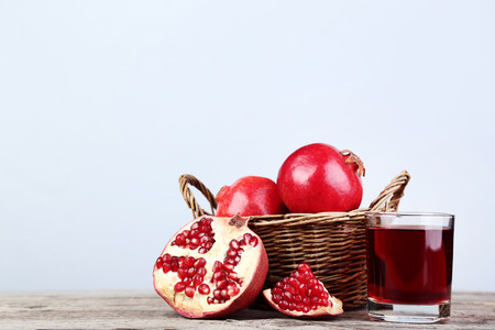 Pomegranate fruit and juice in glass on grey wooden tableの写真素材