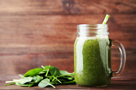 Spinach smoothie in glass jar on brown wooden tableの写真素材