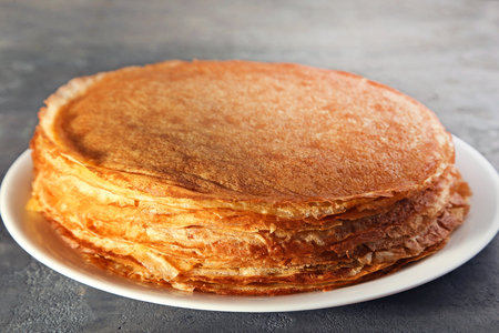 Heap of pancakes in plate on grey wooden tableの写真素材