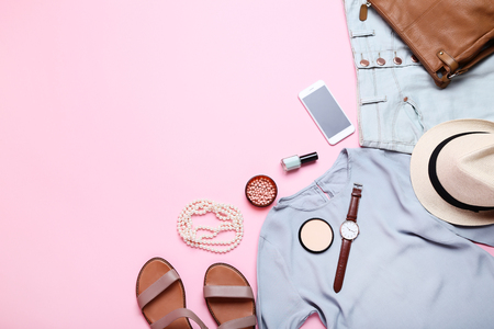 Modern women's clothes with makeup cosmetics and accessories on pink backgroundの写真素材
