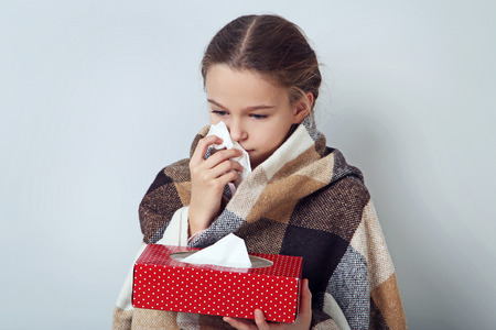 Young sick girl with handkerchief on grey backgroundの写真素材
