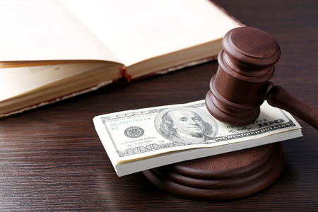 Judge gavel with dollars and book on wooden tableの写真素材