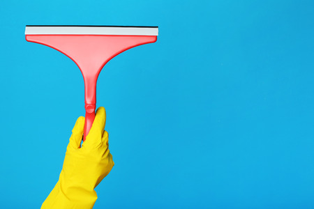 Female hand holding cleaning tool for windows on blue backgroundの写真素材