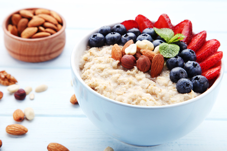 Oatmeal with berries and nuts in bowl on wooden tableの写真素材