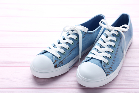 Pair of blue sneakers on pink wooden tableの写真素材
