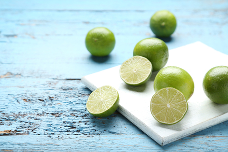 Ripe limes with cutting board on blue wooden tableの写真素材