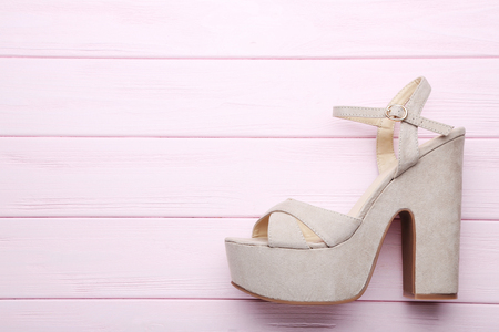 Beige high heel shoes on pink wooden tableの写真素材
