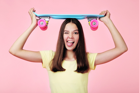 Young girl with skateboard on pink backgroundの写真素材