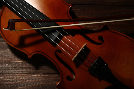 Violin with bow on brown wooden tableの写真素材