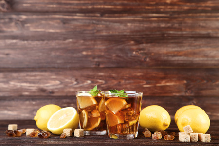 Ice tea in glasses with lemon and mint leafs on wooden tableの写真素材