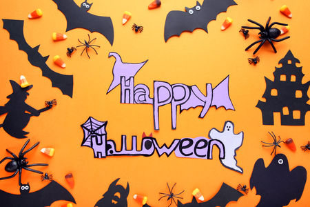 Inscription Happy Halloween with candies and paper decorations on orange backgroundの写真素材